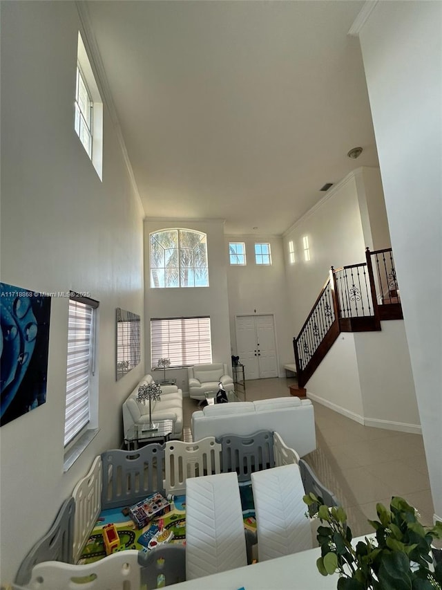 living room with a high ceiling, tile patterned floors, and crown molding