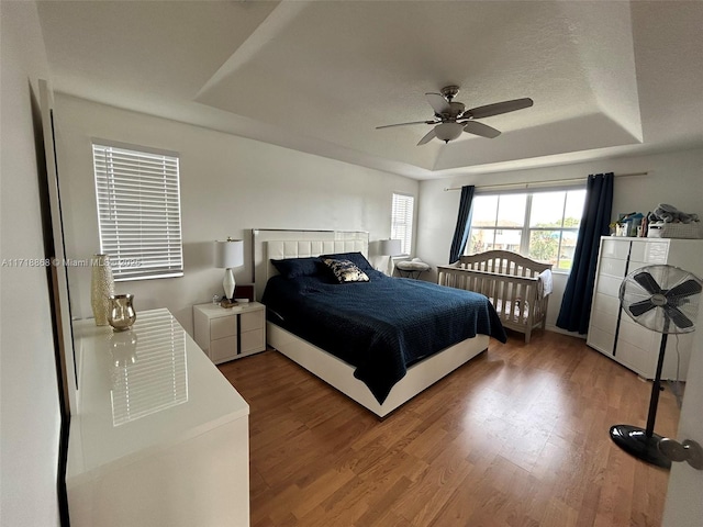 bedroom featuring a tray ceiling, ceiling fan, and hardwood / wood-style flooring