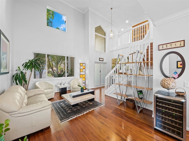 living room featuring hardwood / wood-style floors, beverage cooler, crown molding, and a high ceiling