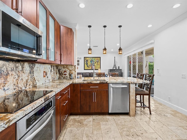 kitchen with a kitchen breakfast bar, kitchen peninsula, hanging light fixtures, and appliances with stainless steel finishes