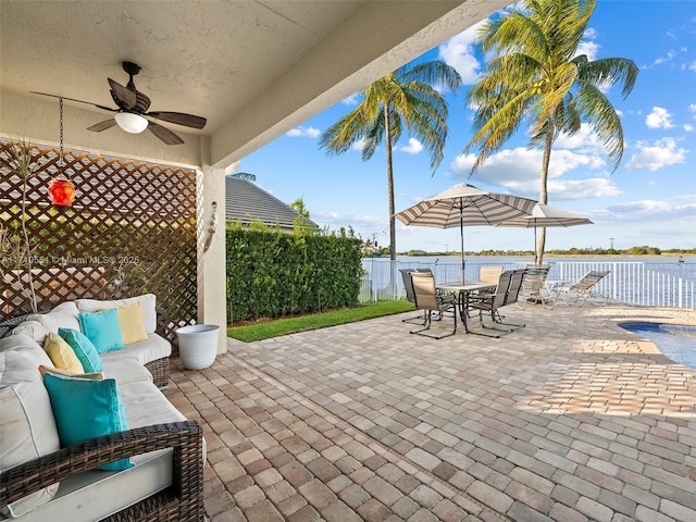 view of patio / terrace with ceiling fan, a water view, and an outdoor living space