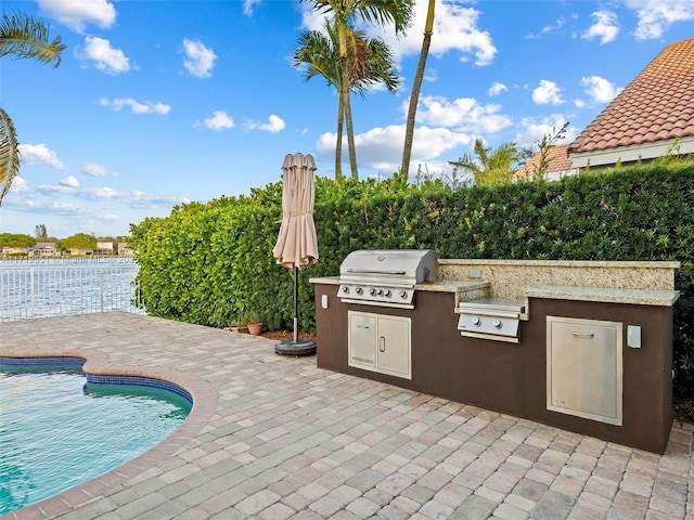 view of patio with an outdoor kitchen, a fenced in pool, and a grill