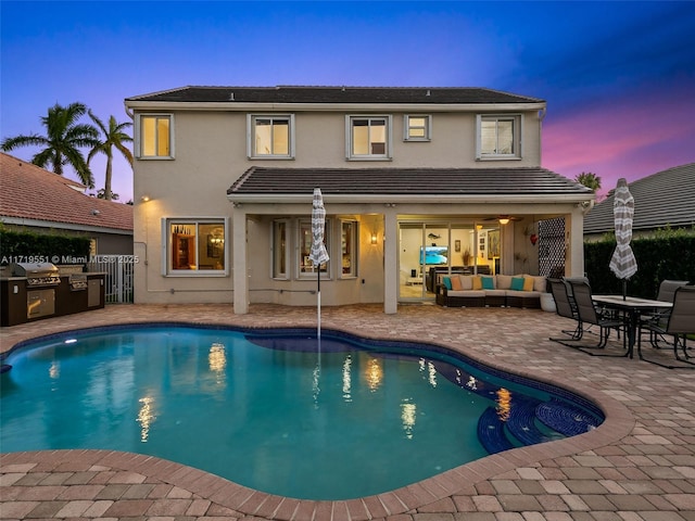 pool at dusk featuring a patio area and an outdoor hangout area