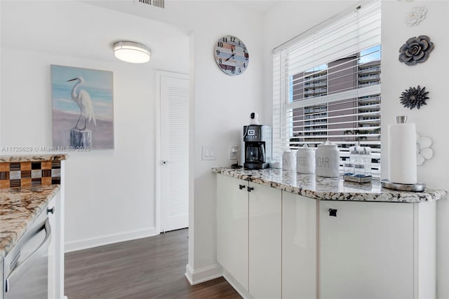 kitchen with dishwashing machine, light stone countertops, white cabinetry, and dark wood-type flooring