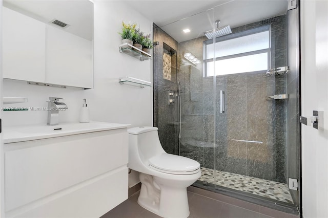 bathroom with tile patterned floors, a shower with door, vanity, and toilet