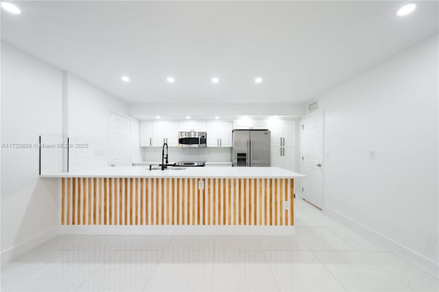 kitchen featuring white cabinetry, kitchen peninsula, sink, and appliances with stainless steel finishes