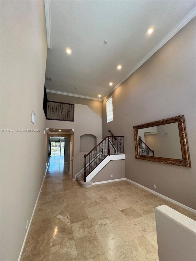 stairway with crown molding and a towering ceiling