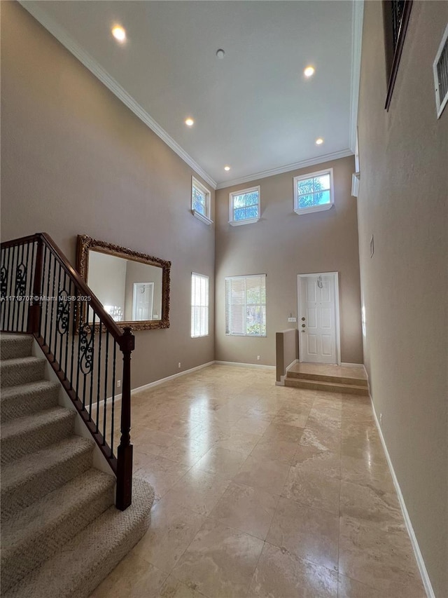 foyer with crown molding and a towering ceiling