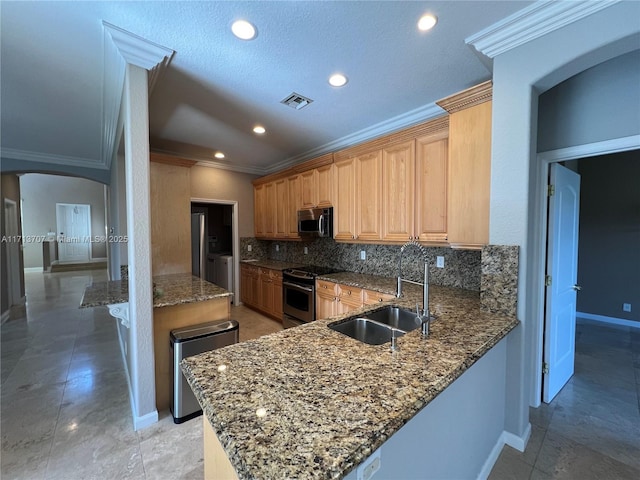 kitchen with decorative backsplash, kitchen peninsula, stainless steel appliances, sink, and dark stone countertops