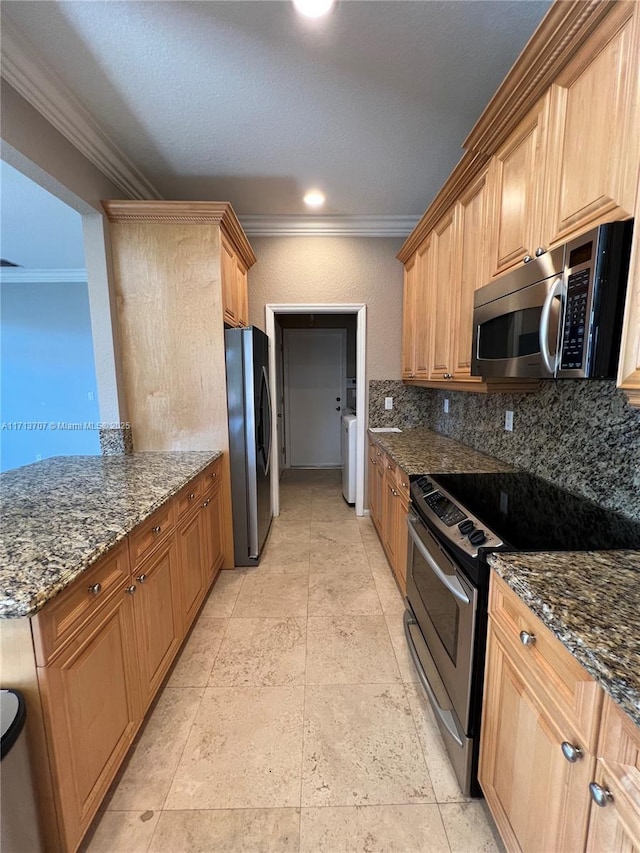 kitchen with stainless steel appliances, dark stone countertops, crown molding, washer / dryer, and decorative backsplash