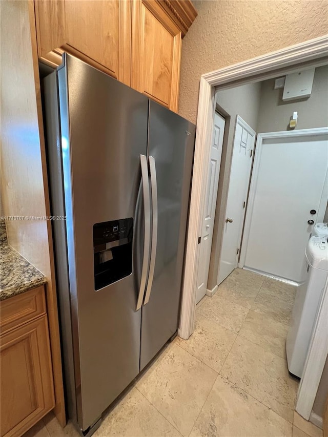 kitchen with stainless steel fridge and stone countertops