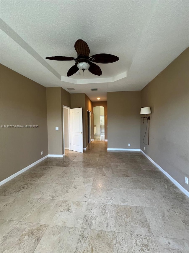 spare room featuring a raised ceiling, ceiling fan, and a textured ceiling