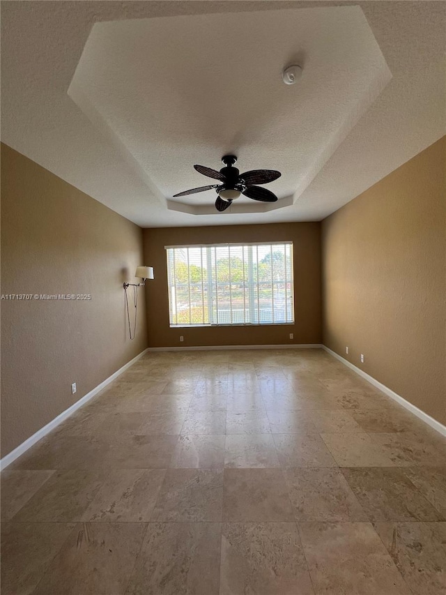 spare room featuring ceiling fan and a tray ceiling