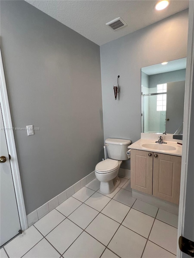 bathroom with tile patterned flooring, vanity, toilet, and a textured ceiling