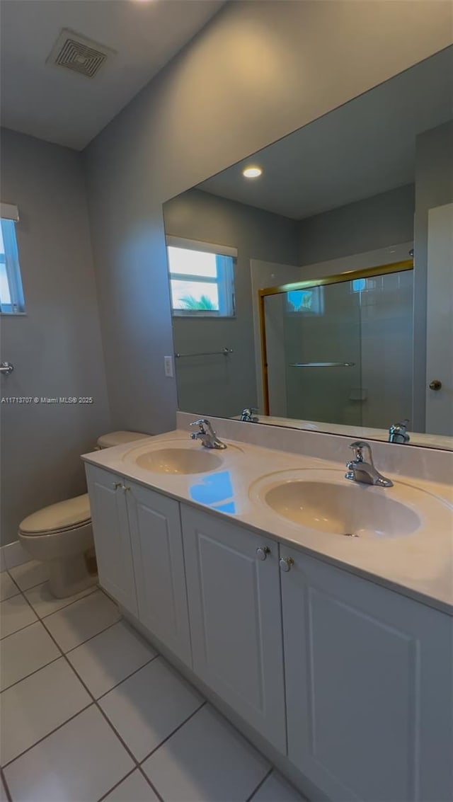 bathroom with tile patterned flooring, vanity, toilet, and a shower with door