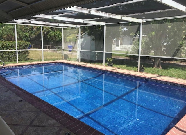 outdoor pool featuring a lanai, an outbuilding, and a storage unit