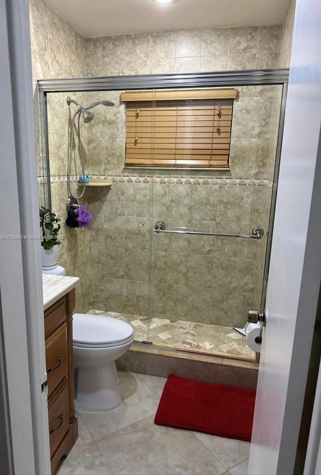 bathroom with a shower stall, tile patterned floors, vanity, and toilet