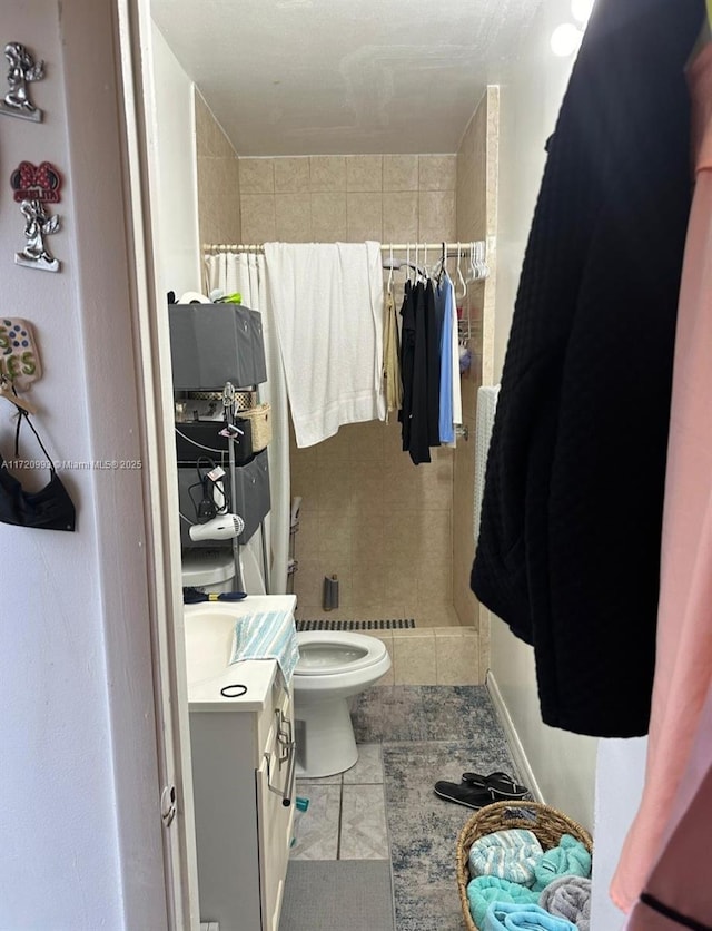 full bath featuring tile patterned flooring, toilet, tiled shower, and vanity