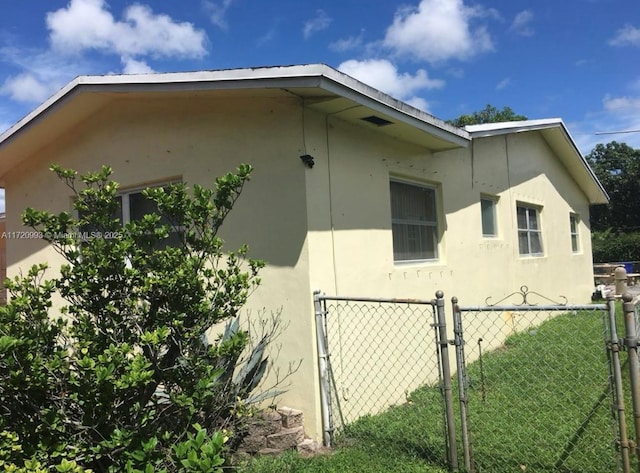 view of side of home featuring fence and stucco siding