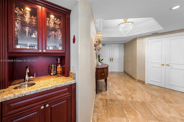 bar with light stone countertops, a tray ceiling, crown molding, sink, and pendant lighting