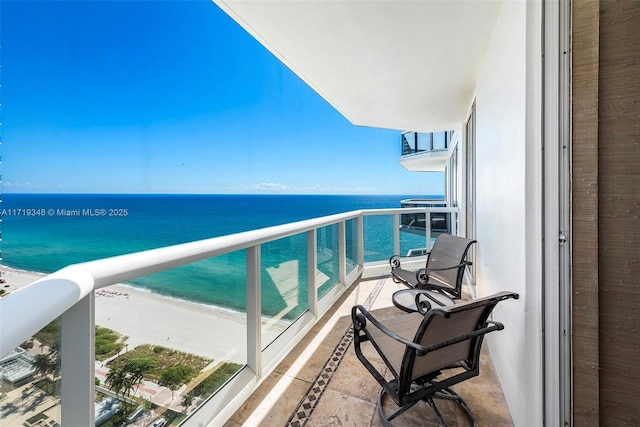 balcony with a water view and a view of the beach