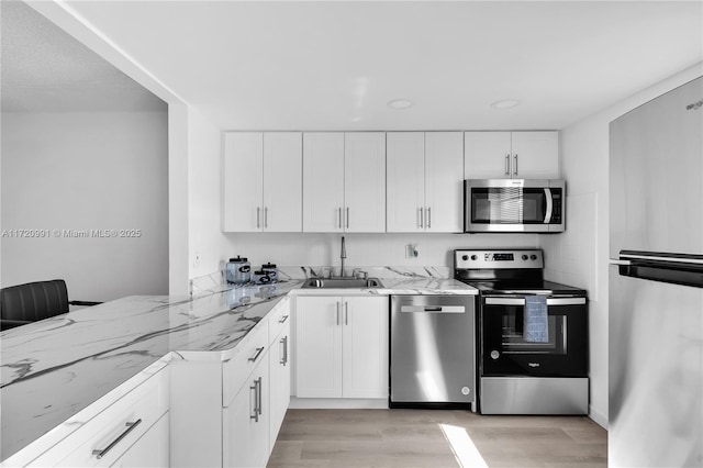 kitchen featuring white cabinets, stainless steel appliances, light stone countertops, and sink