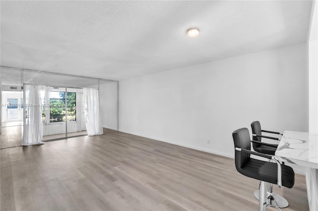 home office with light hardwood / wood-style flooring and a textured ceiling