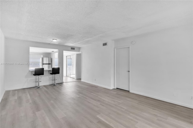 unfurnished living room featuring light hardwood / wood-style floors and a textured ceiling