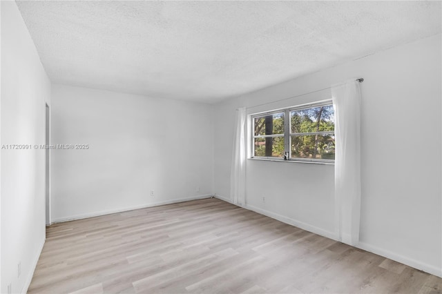 unfurnished room featuring a textured ceiling and light hardwood / wood-style flooring