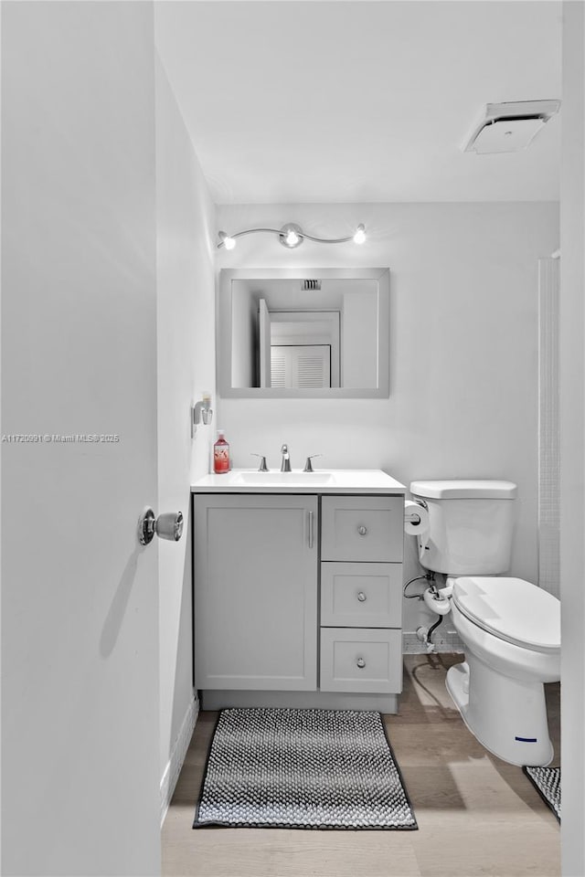 bathroom with vanity, toilet, and wood-type flooring