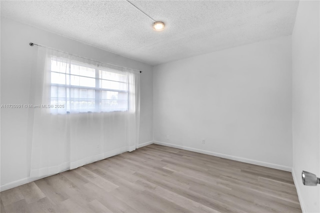 unfurnished room with light hardwood / wood-style flooring and a textured ceiling