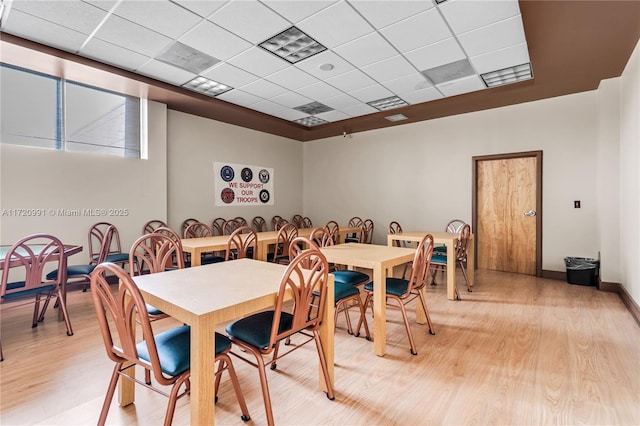 dining room with a drop ceiling and light hardwood / wood-style flooring