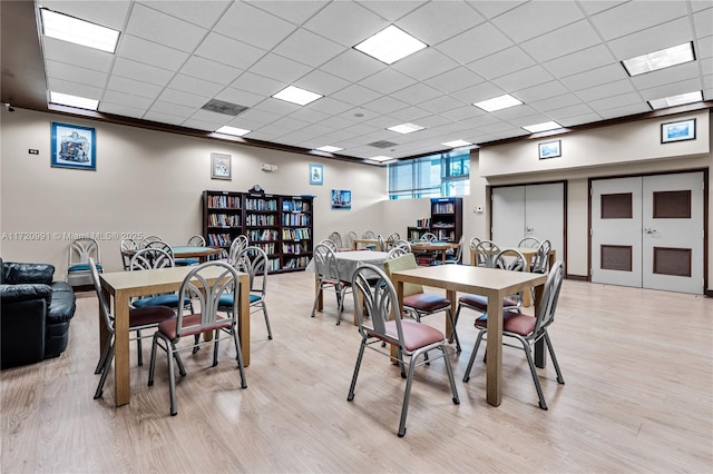 dining space with a paneled ceiling and light hardwood / wood-style flooring