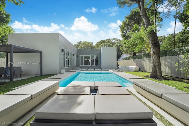 rear view of house with an outdoor hangout area, a fenced in pool, and a patio area