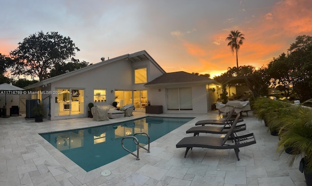 pool at dusk with a patio area