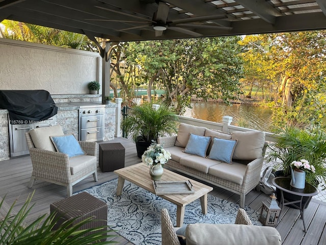 wooden terrace with an outdoor hangout area, a water view, a grill, and exterior kitchen