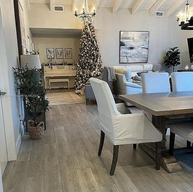 dining space featuring beam ceiling, wood-type flooring, and an inviting chandelier