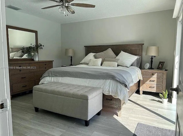 bedroom with ceiling fan, a textured ceiling, and light hardwood / wood-style flooring