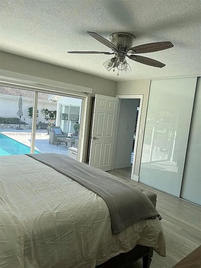 bedroom with access to outside, ceiling fan, light hardwood / wood-style flooring, and a textured ceiling