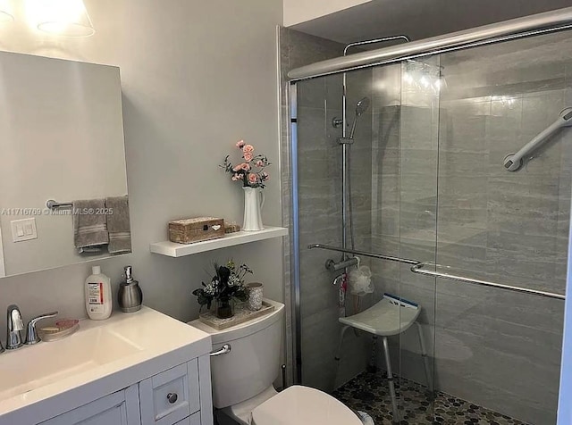 bathroom with toilet, an enclosed shower, and vanity