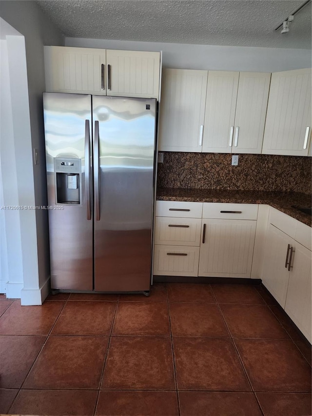 kitchen with white cabinets, stainless steel fridge with ice dispenser, a textured ceiling, and dark tile patterned flooring