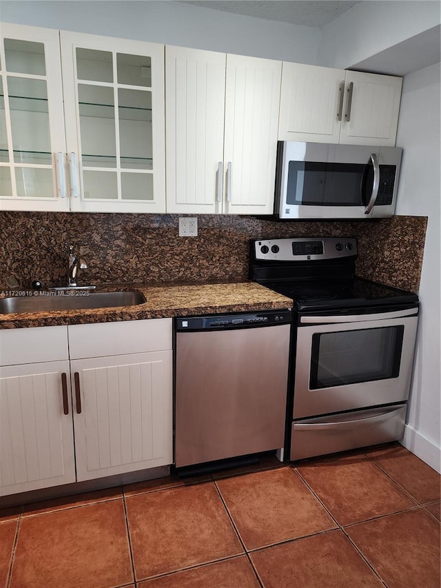 kitchen featuring dark tile patterned flooring, white cabinetry, sink, and appliances with stainless steel finishes