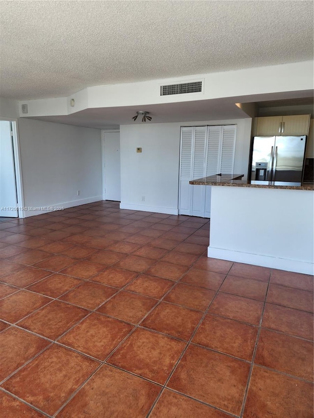 unfurnished living room with dark tile patterned floors and a textured ceiling