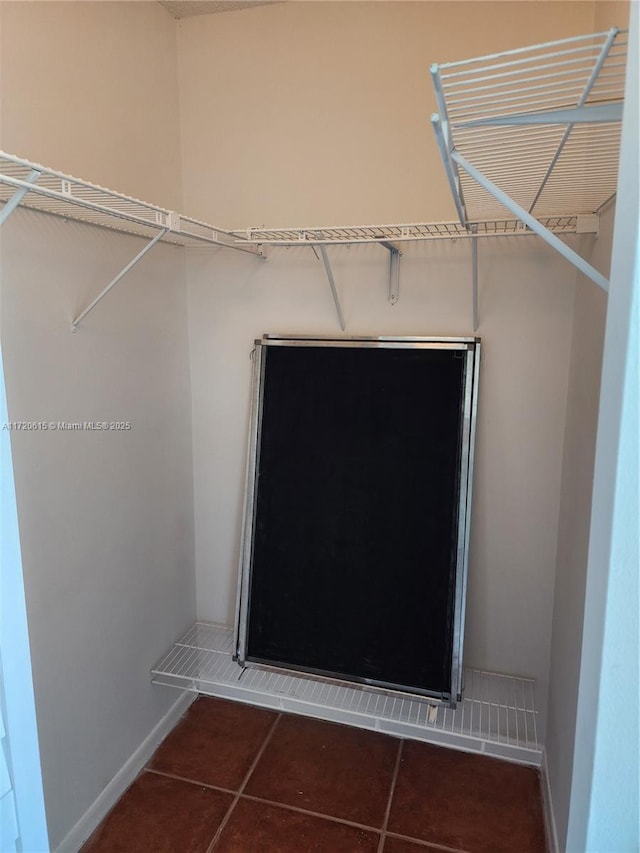 spacious closet featuring dark tile patterned flooring