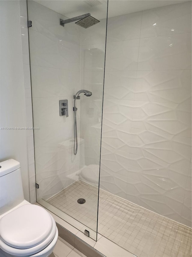 bathroom with a tile shower, tile patterned flooring, and toilet