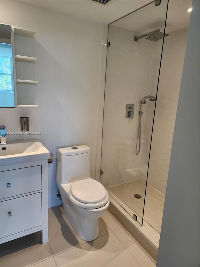 bathroom with tile patterned flooring, vanity, tiled shower, and toilet