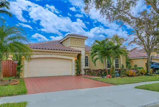 mediterranean / spanish-style house featuring a garage, decorative driveway, a tile roof, and stucco siding