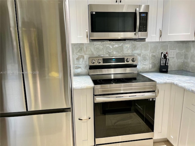 kitchen with white cabinetry, decorative backsplash, stainless steel appliances, and light stone counters