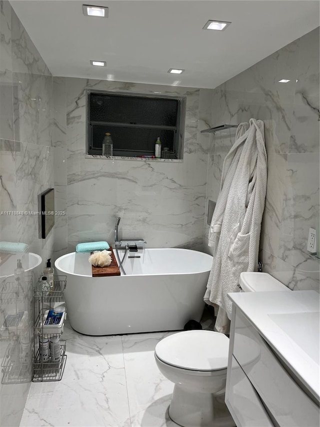 bathroom featuring a tub to relax in, vanity, and toilet