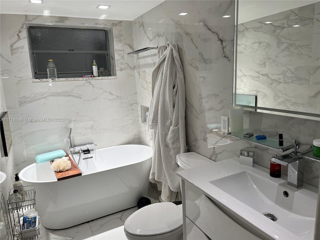 bathroom featuring vanity, a tub to relax in, and toilet